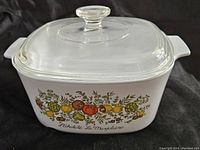 3 quart white glass casserole dish showing colorful Spice of Life vegetable pattern and text on the side with clear glass lid.