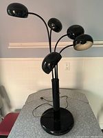 Front view of the 1980s black table lamp showing five adjustable eyeball-shaped lamp heads with white interior on flexible arms.