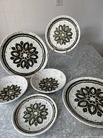 Full view of the six-piece Biltons stoneware set on a table showing two dinner plates, two bowls, and two side plates with brown floral motifs.