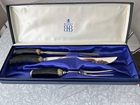 Full view of open Birks carving set with knife, fork, sharpening steel in original navy blue box with blue satin and cream silk lining showing Birks logo on lid interior.