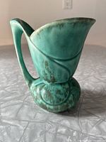 Side view of the vintage green Crown Devon pottery jug showing the handle and textured base.