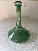 Full view of the tall green glass decanter with stopper, showing bulbous base and narrow neck.
