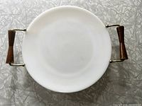Top-down view of the round, white milk glass tray with wooden handles against a textured surface showing minor wear on wood and excellent glass condition.