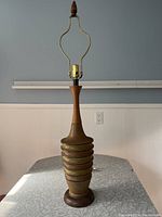 Full side view of the mid-century ceramic table lamp showing entire lamp including wood base and finial, ceramic textured body with horizontal rings.