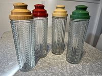 Four MEDCO glass cocktail shakers with ridged Art Deco style and colored plastic recipe caps and strainers