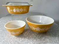 Front view of the 1.5 QT casserole dish with lid and two mixing bowls showing the yellow base color and white floral pattern.