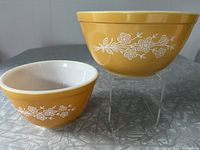 Two Pyrex mixing bowls in Butterfly Gold pattern displayed on table, showing exterior pattern and color.