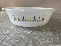 Side view of Fire King Candle Glow casserole dish showing blue and gold starburst pattern on white milk glass.