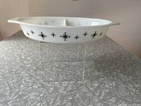 Side view of the white Pyrex divided casserole dish with black Compass pattern along the side, showing the 2 compartments and handles.