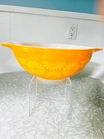 Side view of bright yellow Pyrex Daisy Pattern mixing bowl showing floral white daisies around circumference.