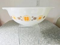 Side profile of white Pyrex mixing bowl with orange and brown Town and Country pattern, showing bowl shape and pouring spout.