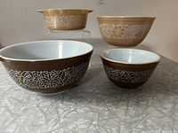 Four Pyrex Woodland Pattern mixing bowls arranged on surface, showing pattern and colors.