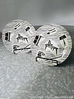 Two round ceramic dishes with retro Homemaker pattern showing furniture and household item silhouettes in black on white background.