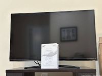 Samsung 40 inch Series 6 LED TV front view with user manual placed on the TV stand in front of the screen.