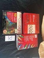 Three boxes of indoor Christmas lights from Noma, Living, and Mainstay brands, showing packaging and quantity labels.