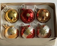 Six vintage glass Christmas ornaments in original packaging with red, gold, and bronze tones and gold glitter detailing.