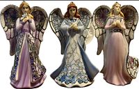 Front view of three Bradford Editions porcelain angel ornaments showing detailed painted gowns and wings with sparkly accents.