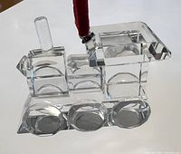 Clear crystal glass train ornament with red ribbon, taken separately.
