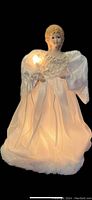 Front view of illuminated angel tree topper showing the lit candle and glowing gown.