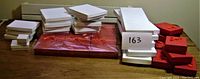 Overview of all gift boxes arranged on table, including stacks of white and red boxes in two sizes, with some shrink-wrapped sets