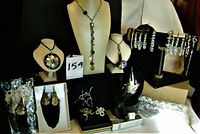 Photo showing assortment of necklaces, earrings, bracelets displayed on stands and flat surfaces