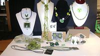 Full display of the green costume jewellery set showing necklaces, earrings, rings, bracelets, and hair pins on stands and table.