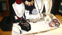 Full lot display showing necklaces on bust forms, multiple bracelets, rings on white boxes, earrings on stands, and belts laid out