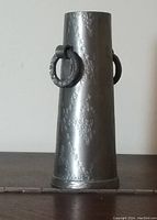Side view of tapered pewter vase showing hammered texture and hanging metal ring handle