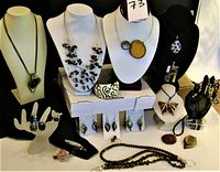Wide photo showing all jewelry pieces displayed on mannequins and stands, includes necklaces, bracelets, rings, earrings, eyeglasses straps, and brooches