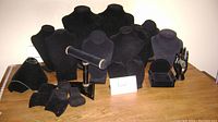 Overview of all black velvet and plastic jewelry display forms arranged on wooden table