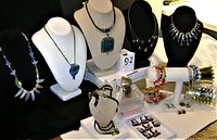 Wide view showing all costume jewellery items including necklaces displayed on busts, bracelets on stands, earrings, and medieval magnets arranged on a table.