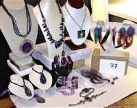 Wide view of the full jewellery lot showing necklaces on busts, rings on display hand, bracelets laid out, and feather earrings on stand.