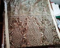 Close-up photo of brown and beige geometric pattern on traditional saree showing intricate circular and triangular motifs with beige border.