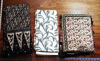 Three folded Indian fabrics/tablecloths with distinct patterns and colors placed side by side