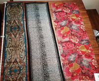 Three scarves displayed on wooden surface showing full length and colors.