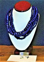 Front view of navy blue multi-strand 6 strands necklace displayed on a stand, with rosewood colored top and ROSEMARY brand tag.