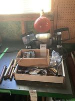 Bench grinder setup on workbench with magnifying shields and box containing parts and wires.