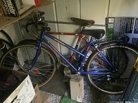 Full view of two bicycles stored indoors, showing men's red Empire Spyder and ladies' blue Mingo Trekking bicycle frames and tires.