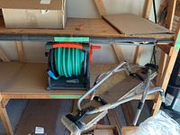 View of full hose reel on a shelf with the ladder stand offs leaning nearby showing overall lot contents.