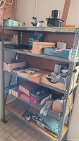 Full view of five-tier metal shelf loaded with boxes, trays, and tools