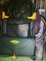 Top view of the lawn sweeper showing the green plastic body with Yardworks logo and black collection bag with folded handle.