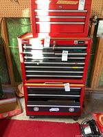 Front view of three-piece red tool cabinet set showing top chest, middle chest and bottom rolling cabinet in garage against pegboard