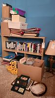 Shelf unit with cardboard boxes, binders and picture frames on floor