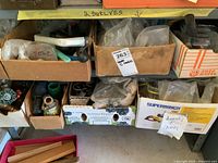 Shelf with multiple boxes containing assorted hardware items including valves, fittings, and clamps