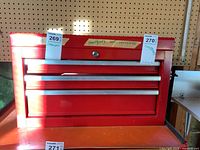 Front view of red metal tool storage cabinet with three closed drawers and 'Contents Not Included' label taped on front.