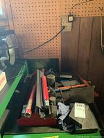 Photo of the table displaying the welding accessories including the shaping tool, sharpening stone, and bracing stand with some packing material.