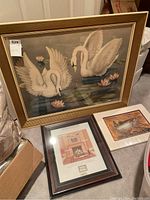 Full view of framed swan artwork alongside two smaller framed prints showing fish and fireplace/hall imagery.
