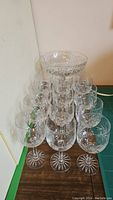 12 stemmed crystal glasses arranged in rows with a crystal pedestal bowl on top showing the entire set.