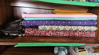 Stack of assorted fabric pieces on a wooden shelf, showing various colors and patterns