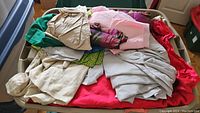 View of assorted folded fabric pieces in and on top of storage bin